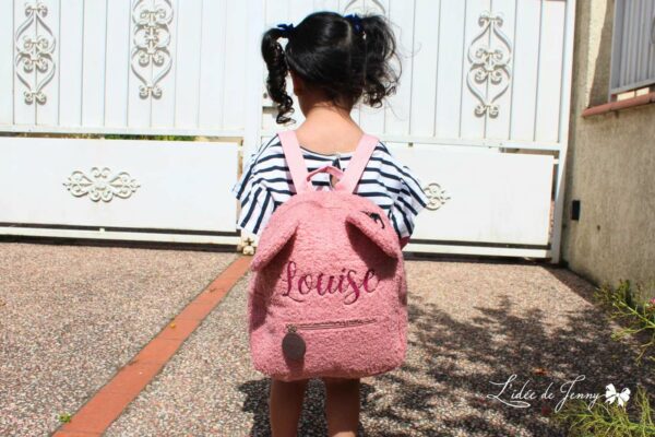 petite fille qui porte le sac à dos ourson rose