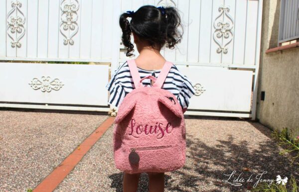 petite fille qui porte le sac à dos ourson rose